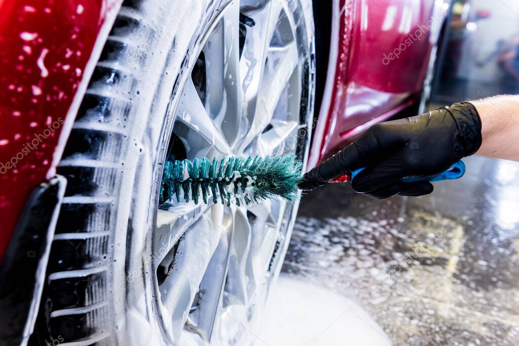 Cleaning the car wheel with a brush and water
