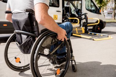 Tekerlekli sandalyedeki bir adam özel bir aracın asansörüne biner. 