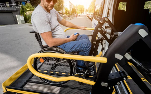Een man in een rolstoel op een lift van een voertuig voor mensen met een handicap — Stockfoto