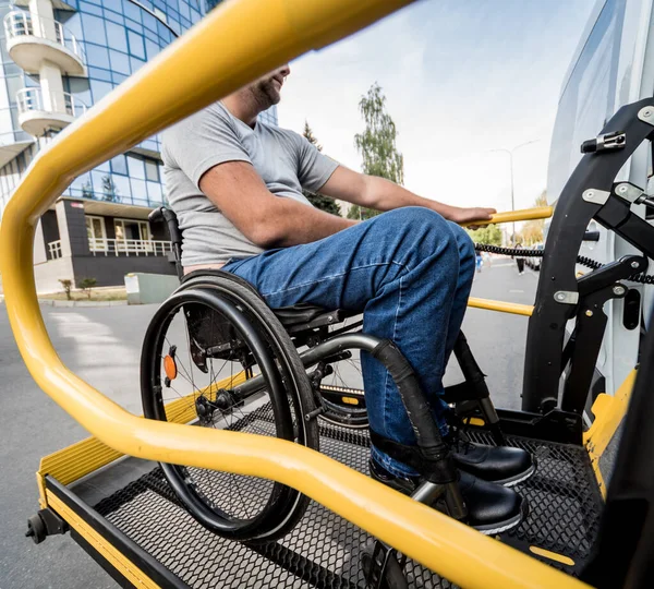 Un hombre en silla de ruedas en un ascensor de un vehículo para personas con discapacidad —  Fotos de Stock
