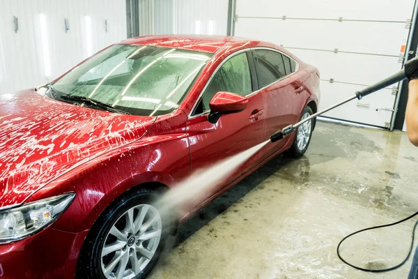 Arbetare tvätta bil med högtrycksvatten vid en biltvätt. — Stockfoto