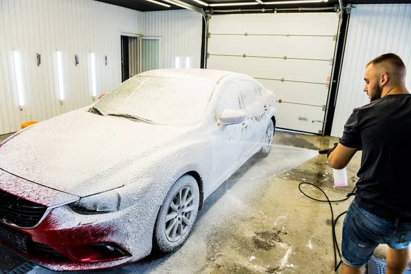 Trabajador de lavado de coches con espuma activa en un lavado de coches. — Foto de Stock