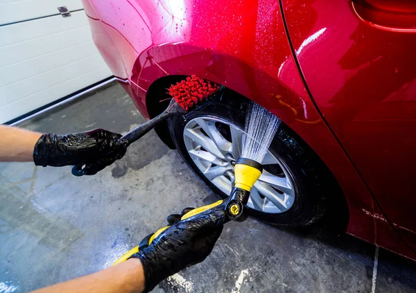 Limpieza de la rueda del coche con un cepillo y agua — Foto de Stock