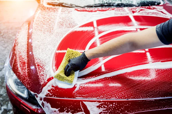 Trabalhador lavar carro vermelho com esponja em uma lavagem de carro — Fotografia de Stock