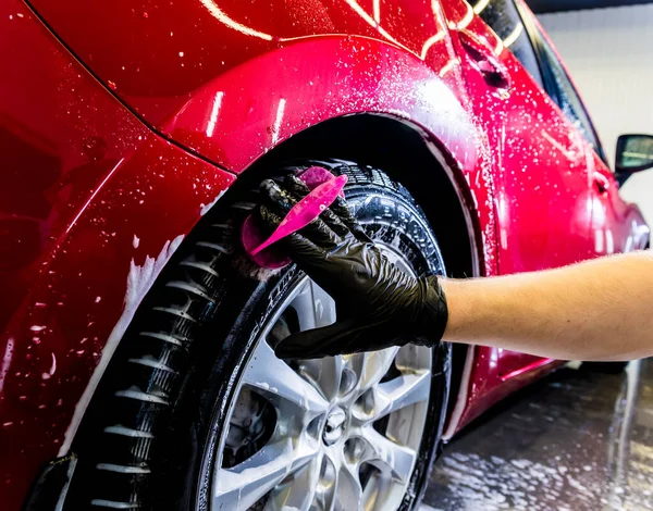 Limpieza de la rueda del coche con un cepillo y agua — Foto de Stock