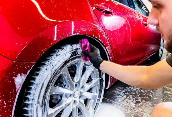 Limpieza de la rueda del coche con un cepillo y agua — Foto de Stock