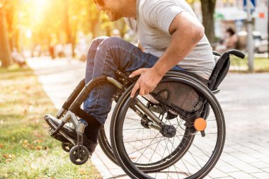 Tekerlekli sandalyedeki engelli adam parkta yürüyor.