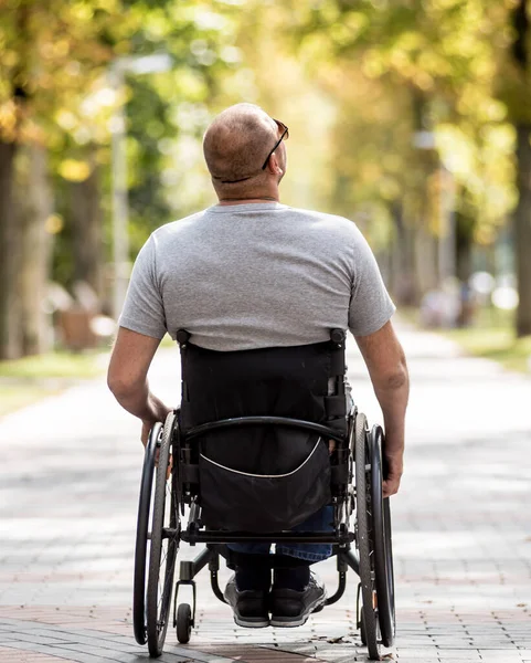 Gehandicapte man in rolstoel loopt in de steeg van het park — Stockfoto