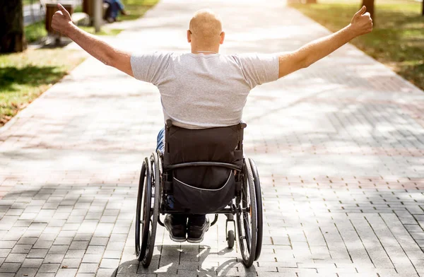 Gehandicapte man in rolstoel loopt in de steeg van het park — Stockfoto