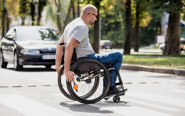 Handicapped man in wheelchair crossing street road