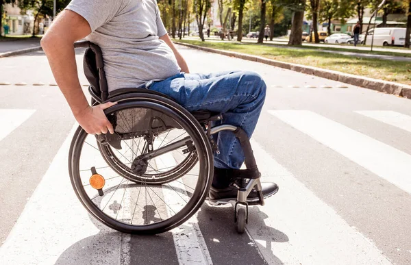 Mozgássérült férfi tolószékben keresztezi az utcát — Stock Fotó