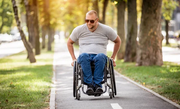 Gehandicapte man in rolstoel loopt in de steeg van het park — Stockfoto