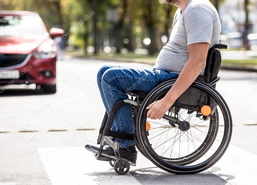 Handicapped man in wheelchair crossing street road