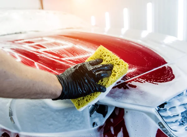 Werknemer wassen rode auto met spons op een car wash — Stockfoto