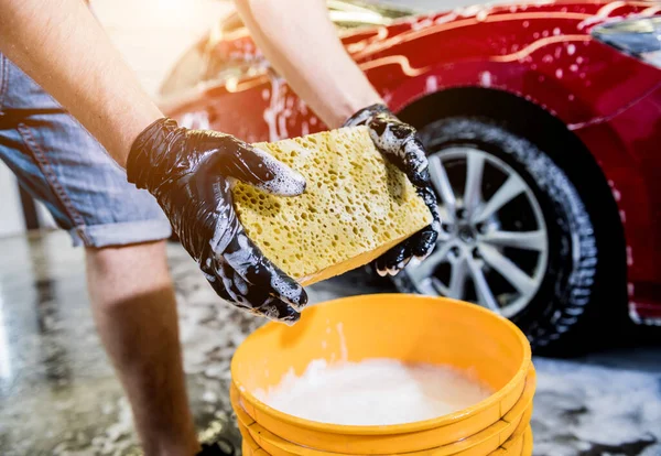 Werknemer wassen rode auto met spons op een car wash — Stockfoto