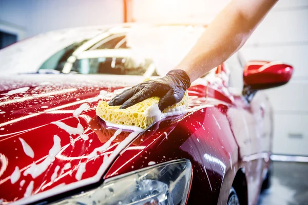 Ouvrier laver voiture rouge avec éponge sur un lavage de voiture — Photo