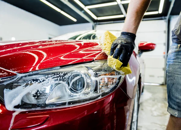 자동차 세차장에서 스펀지를 사용하여 붉은 차를 씻는 작업자 — 스톡 사진