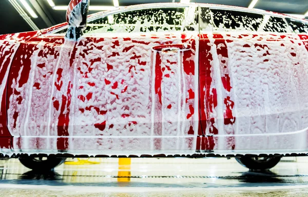 Tvätta röd bil med aktivt skum vid biltvättservice. — Stockfoto