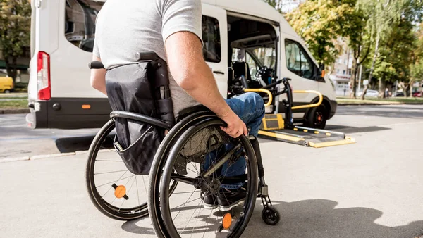Un uomo su una sedia a rotelle si muove verso l'ascensore di un veicolo specializzato — Foto Stock