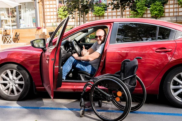 Young handicapped man on drivers seat of his car