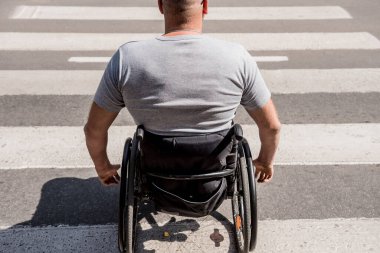 Tekerlekli sandalyedeki engelli adam caddeden karşıya geçiyor.