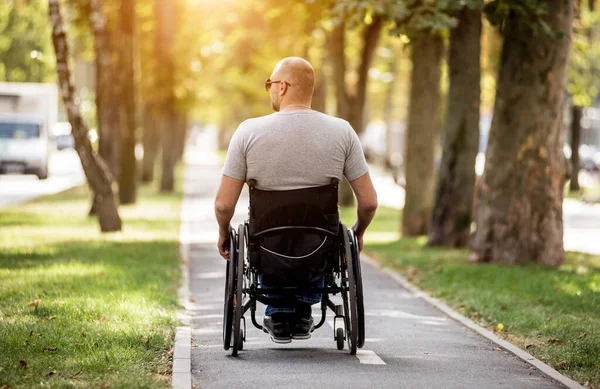 Niepełnosprawny mężczyzna na wózku inwalidzkim w alejce parku — Zdjęcie stockowe