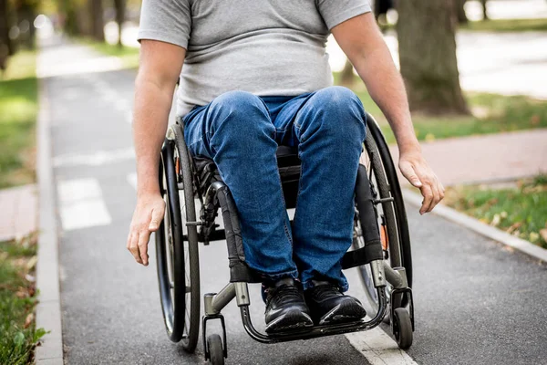Tekerlekli sandalyedeki engelli adam parkta yürüyor. — Stok fotoğraf