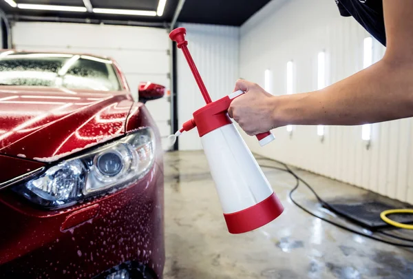Travailleur lavage de voiture avec mousse active sur un lavage de voiture. — Photo