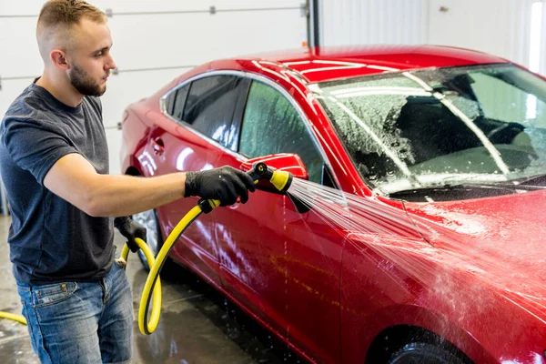 Servisní pracovník mytí aut na myčce aut. — Stock fotografie