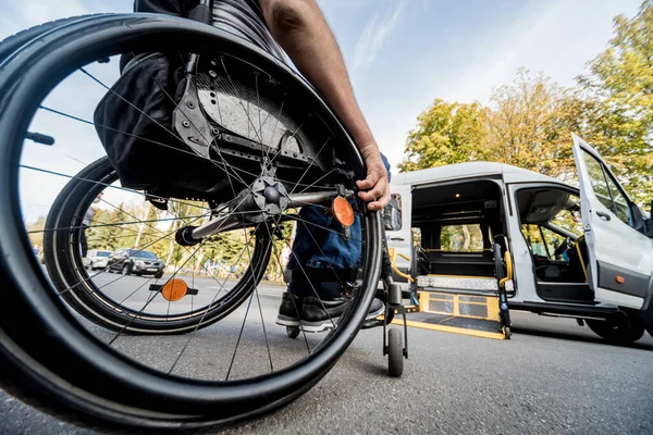 Un uomo su una sedia a rotelle si muove verso l'ascensore di un veicolo specializzato — Foto Stock