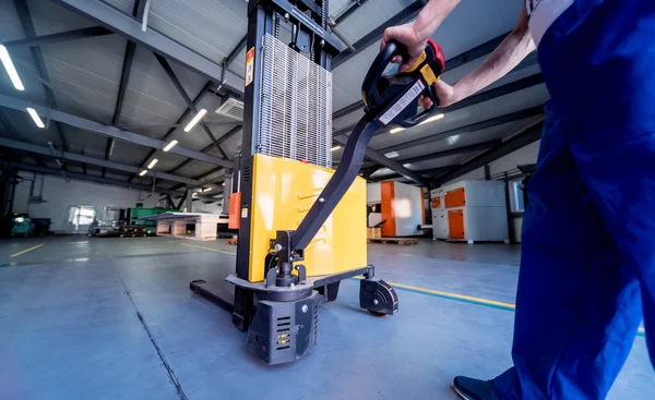 Un trabajador en un almacén utiliza un apilador manual para transportar paletas. — Foto de Stock