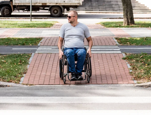 Bezbariérový muž na invalidním vozíku se chystá přejít silnici na pěší křižovatce — Stock fotografie