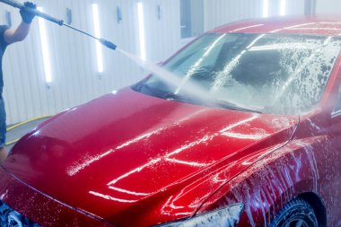 İşçi oto yıkamada yüksek basınçlı suyla araba yıkıyor..