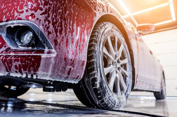 Lavado de coche rojo con espuma activa en el servicio de lavado de coches. — Foto de Stock