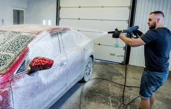 Trabajador de lavado de coches con espuma activa en un lavado de coches. — Foto de Stock