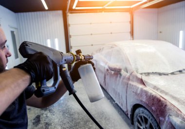 Araba yıkamada köpüklü araba yıkayan bir işçi..