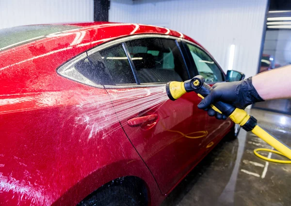 Servicearbetare som tvättar bil på en biltvätt. — Stockfoto