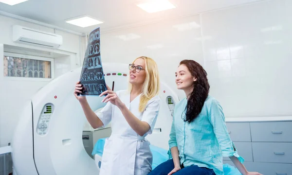 Radiologist with a female patient examining a CT scan