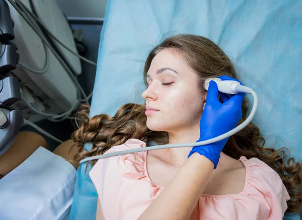 Doctor using ultrasound scanning machine for examining a head of woman