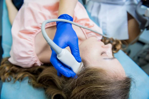 Bir kadının kafasını muayene etmek için ultrason cihazı kullanan bir doktor. — Stok fotoğraf