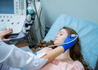 Bir kadının kafasını muayene etmek için ultrason cihazı kullanan bir doktor.