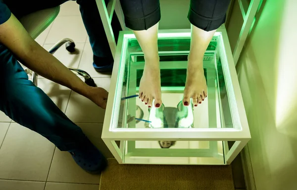 医者は女性の足を植物検査装置で検査してる — ストック写真