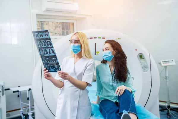 Radiológus egy női beteggel, aki védőmaszkot visel, és CT-vizsgálatot végez. — Stock Fotó