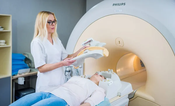 放射科医生让这位年轻妇女准备做核磁共振脑部检查 — 图库照片