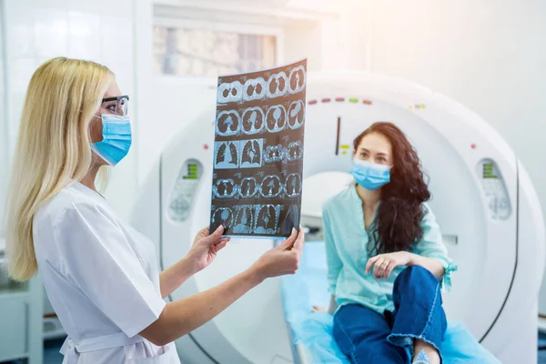 Radiologist with a female patient wearing protective masks examining a CT scan