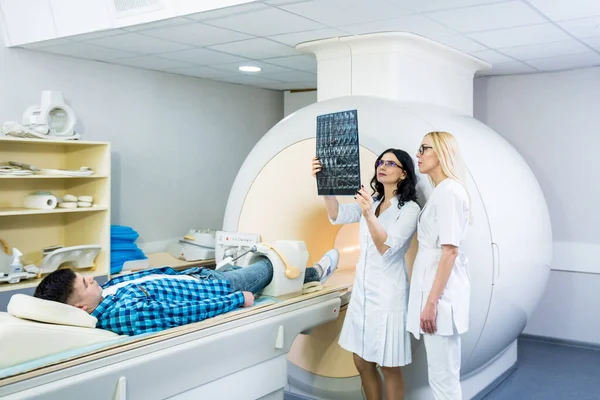 Radioloog met een mannelijke patiënt die een MRI scan onderzoekt — Stockfoto