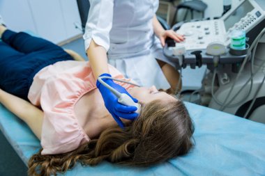 Bir kadının kafasını muayene etmek için ultrason cihazı kullanan bir doktor.