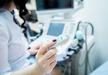 Doktor, bir kadının tiroidini incelemek için ultrason cihazı kullanıyor.