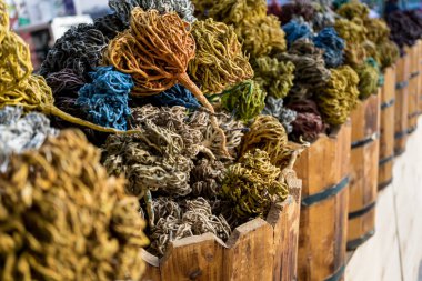 Dekoratif toplara dönüşmüş renkli kurumuş deniz yosunu sokak pazarındaki ahşap sepetlerde yatıyor.