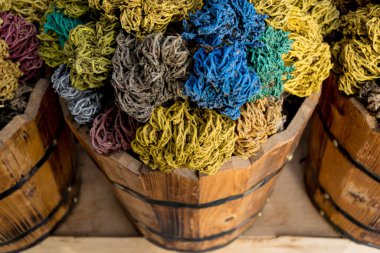 Dekoratif toplara dönüşmüş renkli kurumuş deniz yosunu sokak pazarındaki ahşap sepetlerde yatıyor.